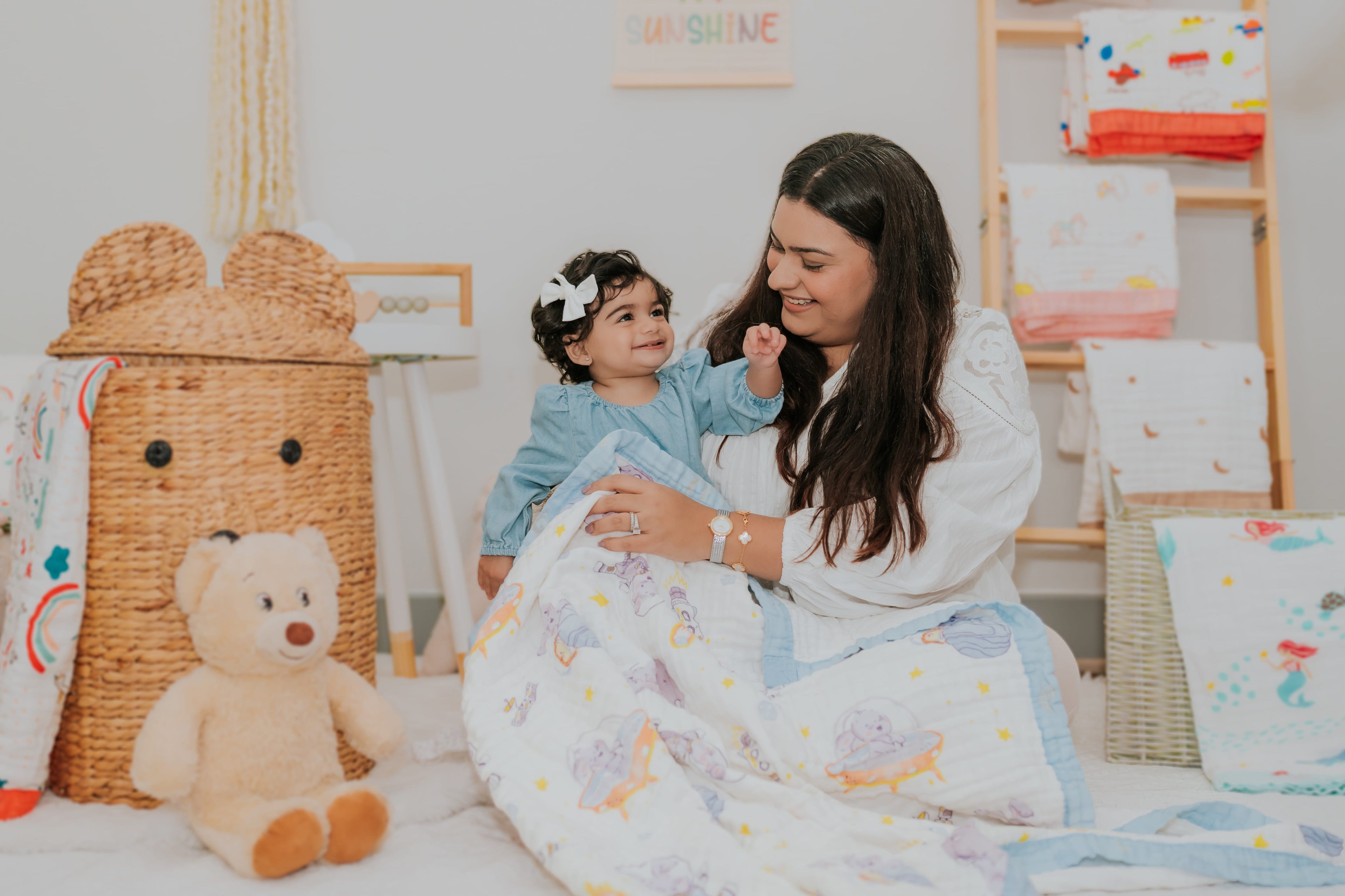 a mother holding a baby while baby is smiling and covered in blanket