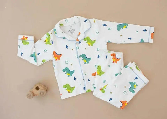 Child wearing dinosaur-themed pajamas standing on a white platform with a plain background