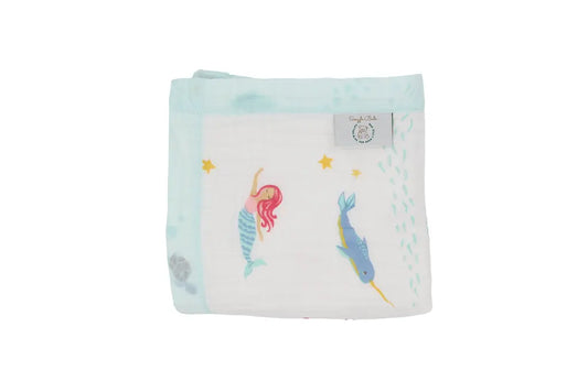 A folded white muslin baby blanket featuring a mermaid and a narwhal under a starry sea pattern, with a light blue border and a visible 'Coco Bongo' brand tag.