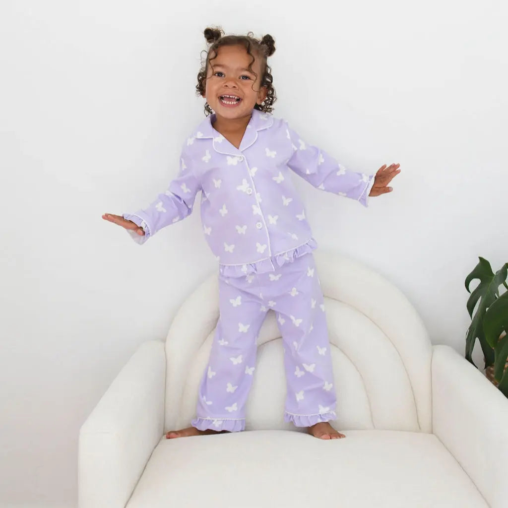 Child wearing purple pajamas with star pattern on a white chair.