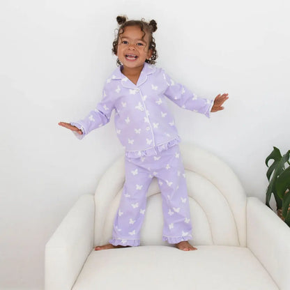 Child wearing purple pajamas with star pattern on a white chair.