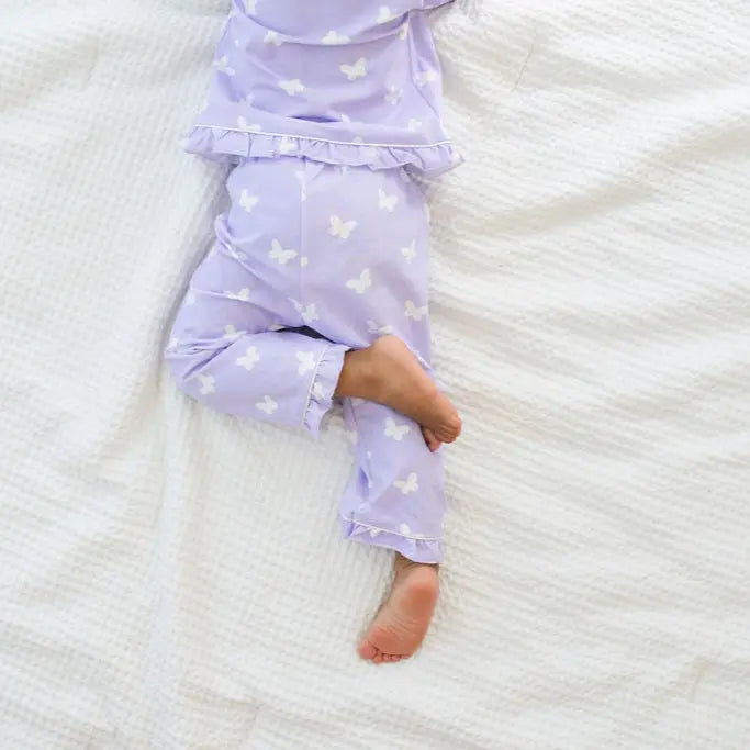 Child wearing purple pajama pants with white patterns on a white textured surface