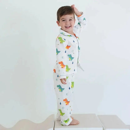 Child wearing dinosaur-themed pajamas standing on a white platform with a plain background