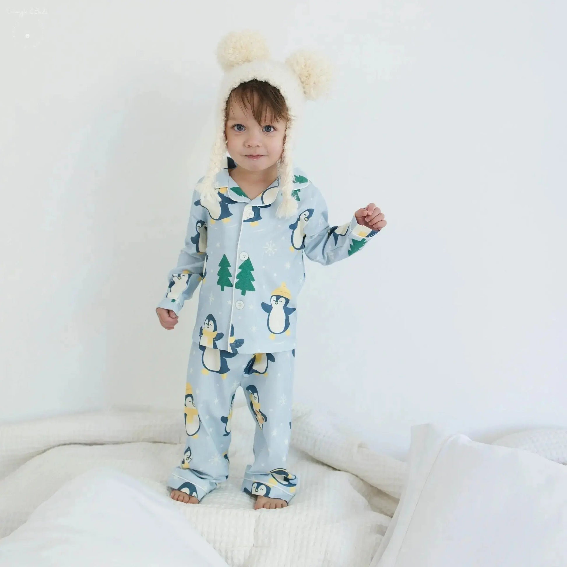 Child wearing a blue penguin onesie with a white background